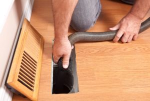 Technician Using Hose To Clean Floor Air Duct