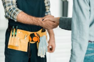 Torso Shot Of Handshake Between Contractor With Tool Belt And Client