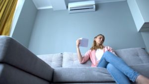 Unhappy Woman Fanning Herself Under Ductless Mini Split