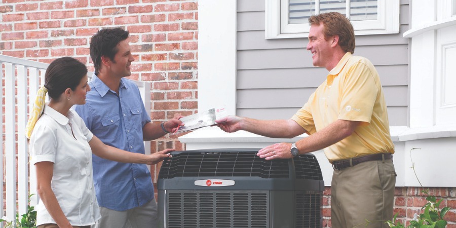 Trane Dealer Talking With Home Owners Next To Trane Unit