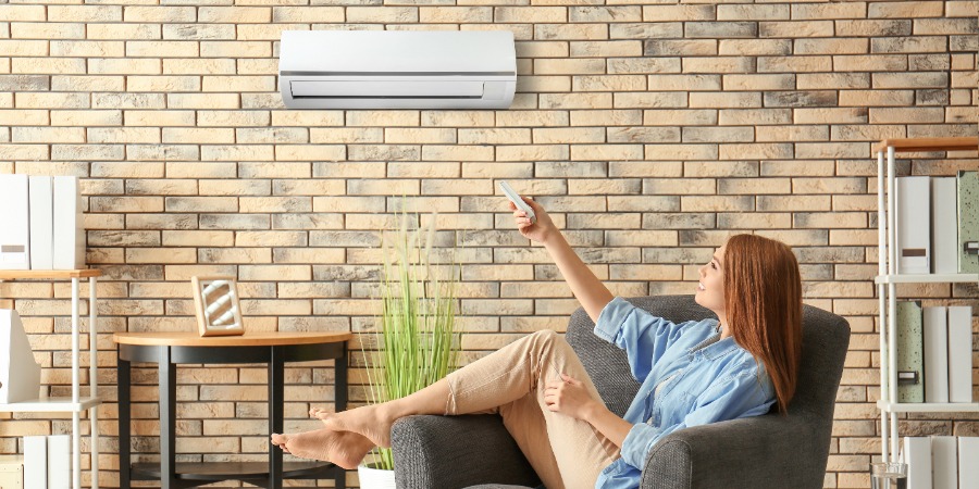 Woman Using Remote To Control Ductless Ac